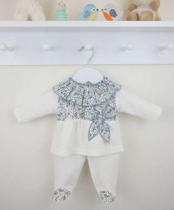 Baby outfit with floral top and white pants on a mannequin against a white background.
