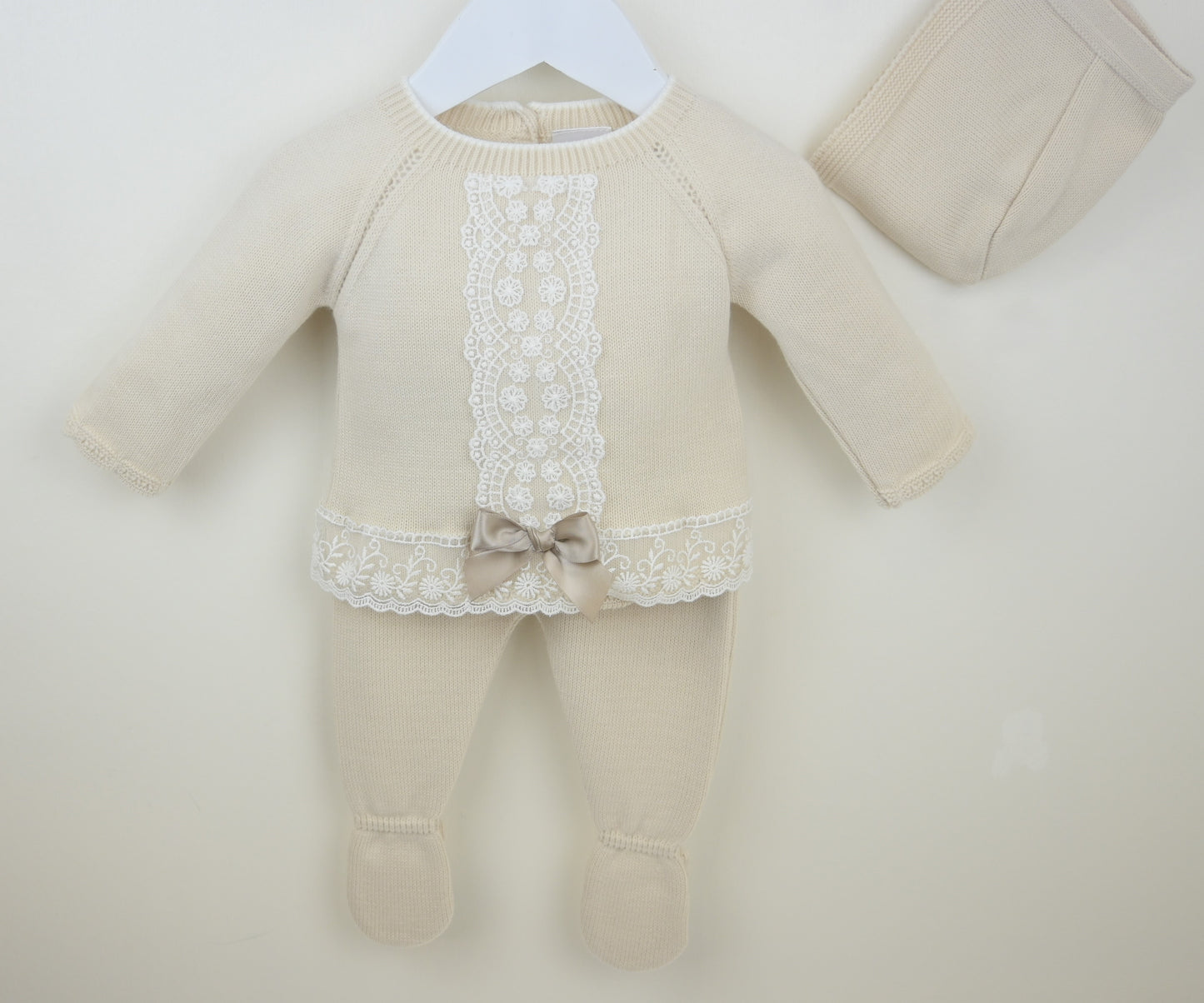 Beige baby outfit with lace details on a white background