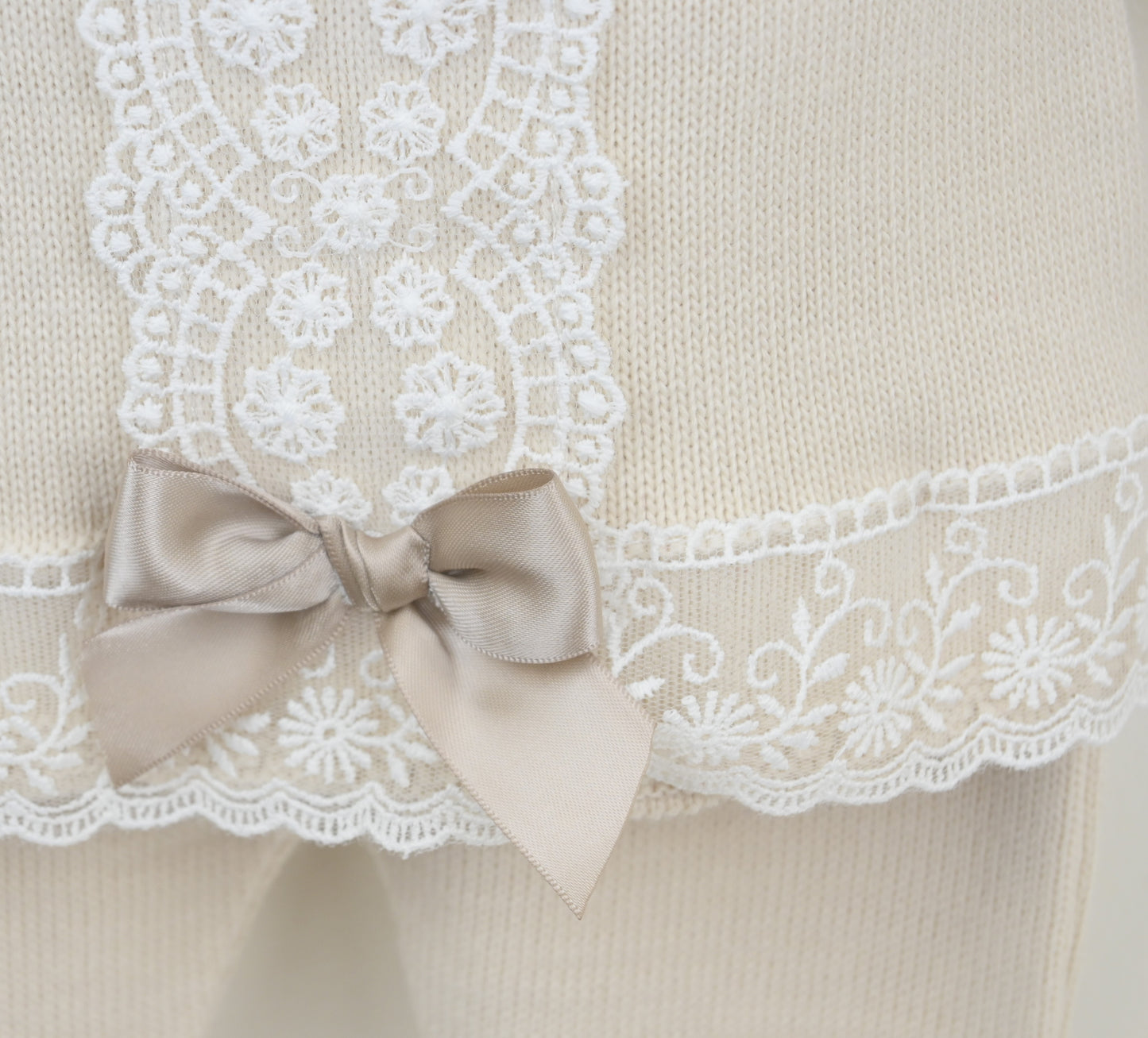 Beige garment with white lace trim and a satin bow