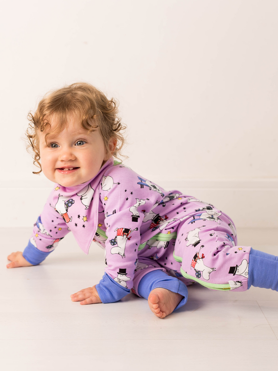 Baby in a purple outfit with moomin cartoon characters on a light background