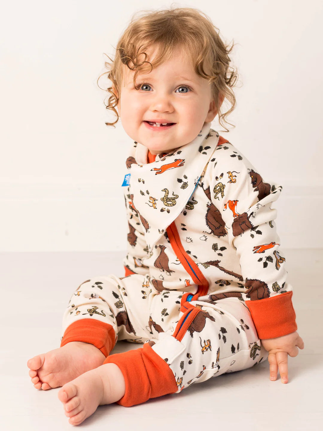 Child wearing a patterned onesie with orange accents on a white background