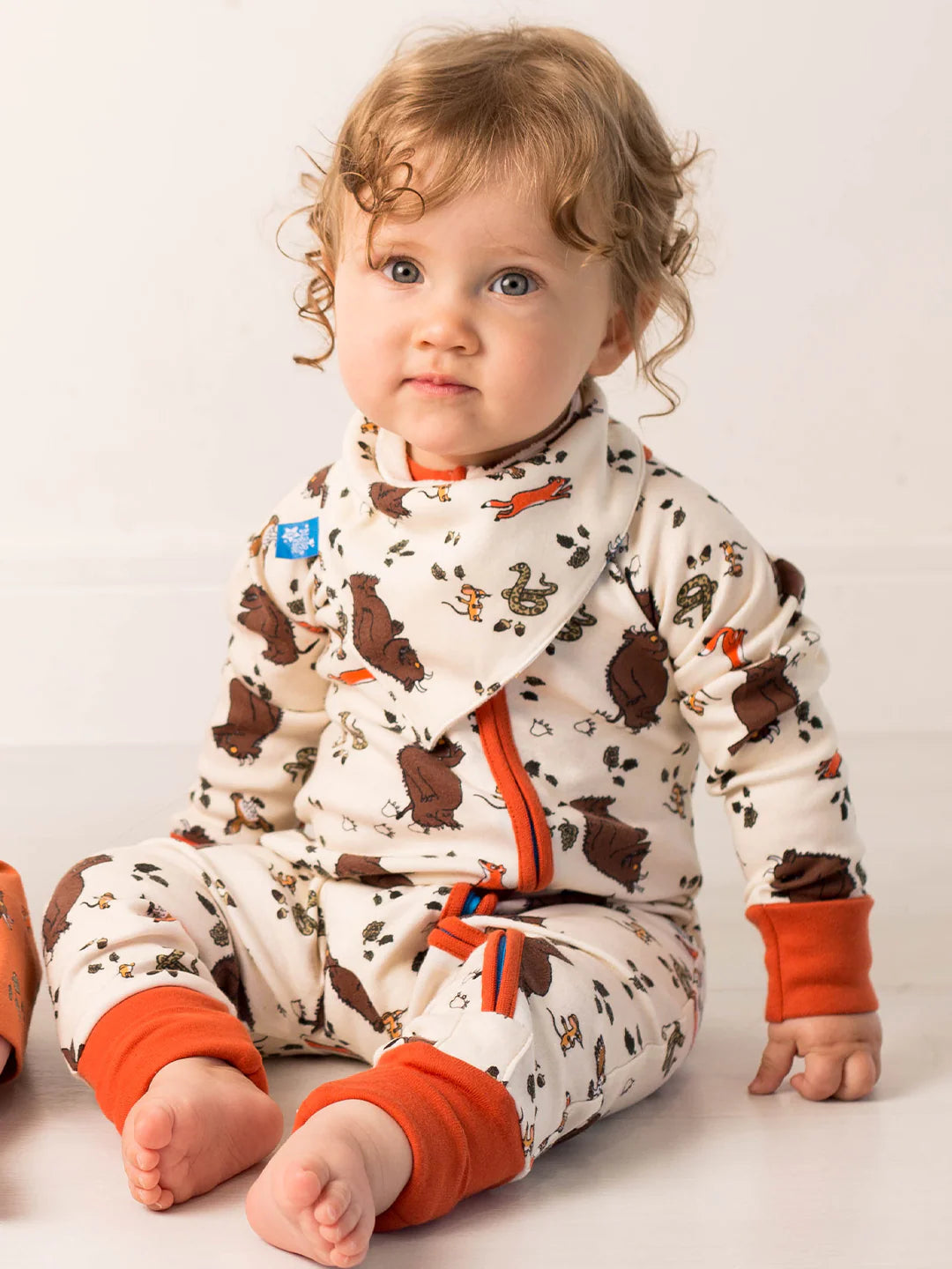 Child wearing a gruffalo patterned outfit with orange accents on a plain background