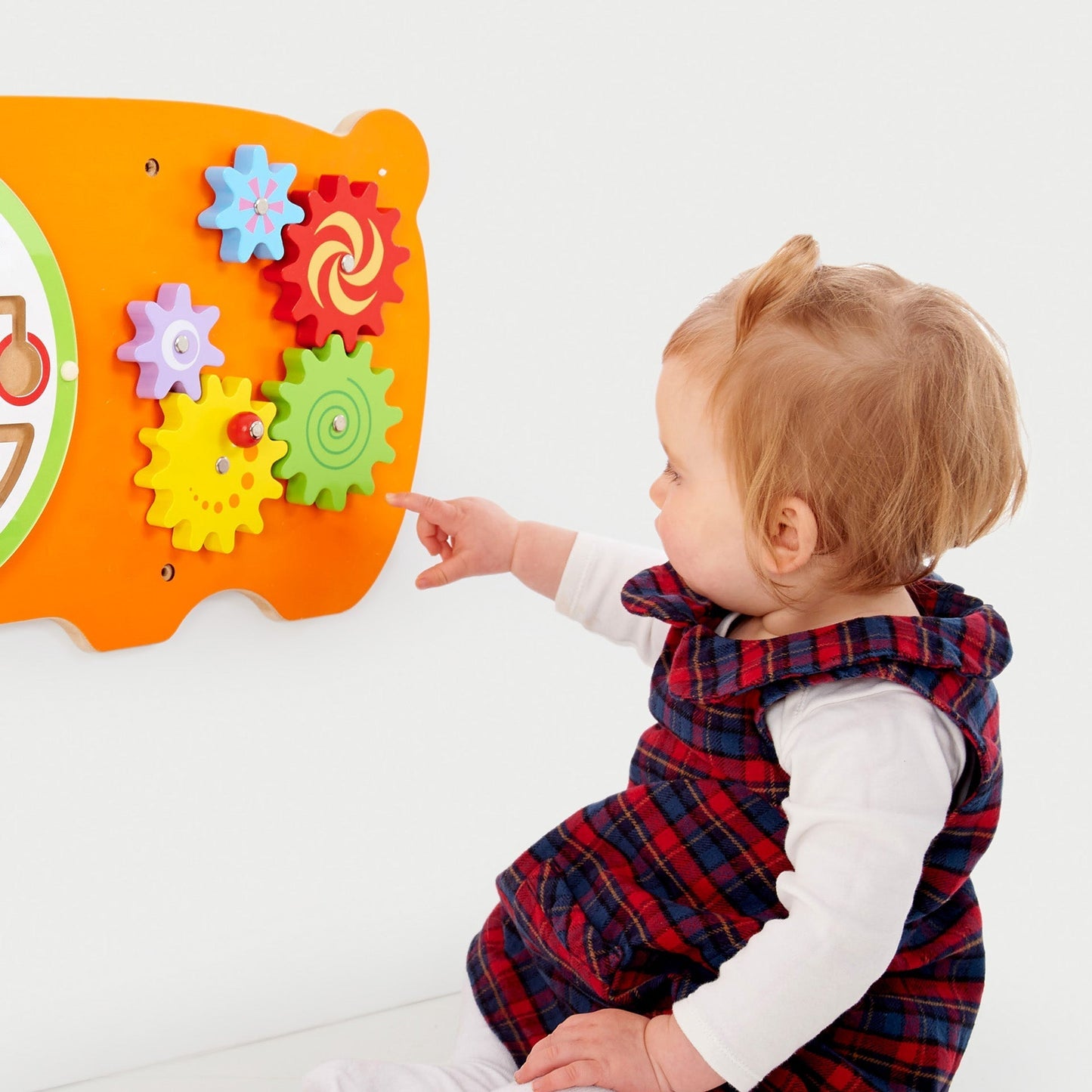 Child interacting with a colorful educational toy featuring gears and flowers on a white background