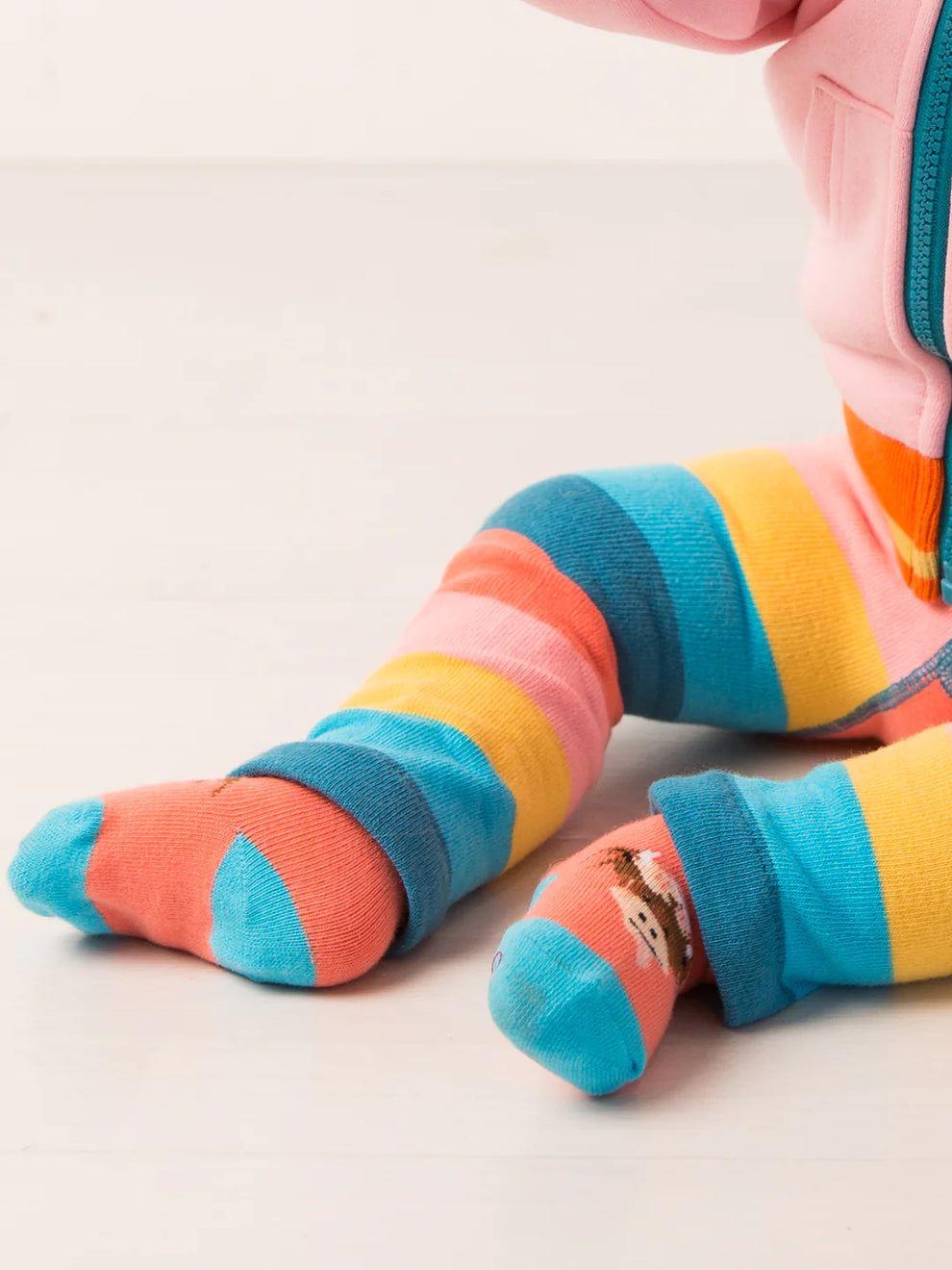 Colorful highland cow socks worn by a child on a light background
