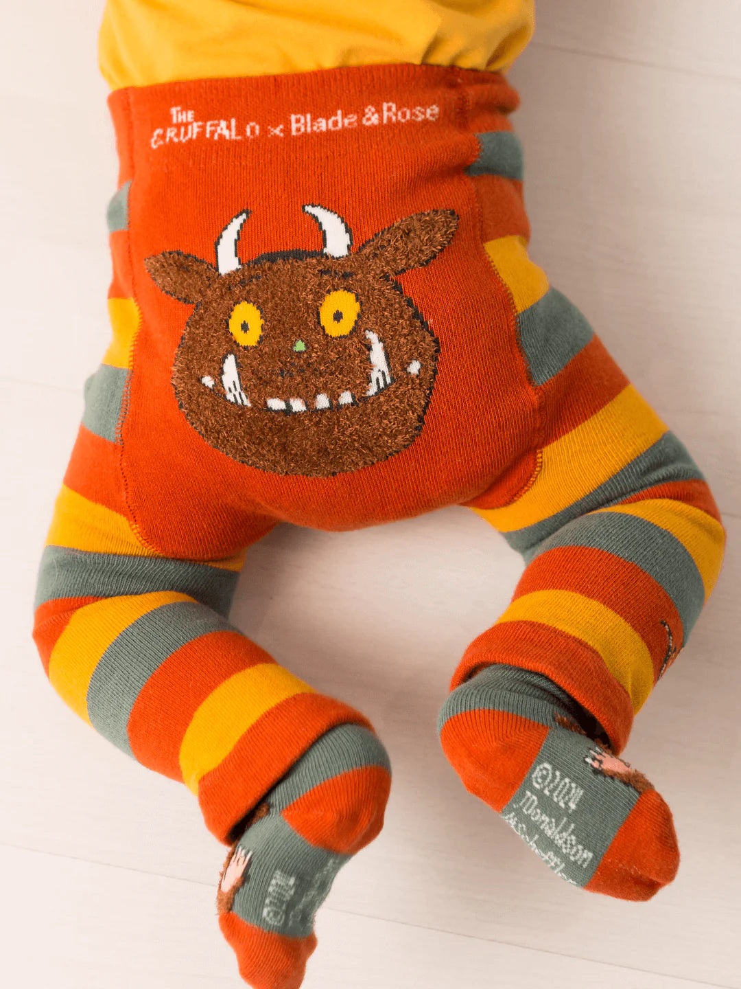 Colorful striped baby leggings with a Gruffalo character on a white background