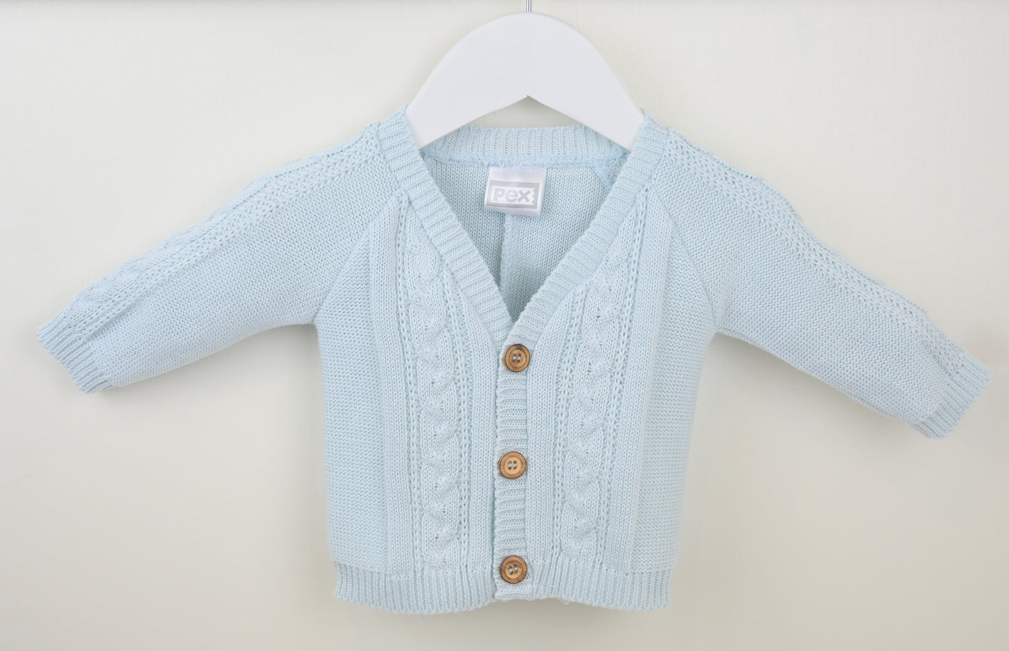 Light blue baby cardigan on a white hanger against a beige background