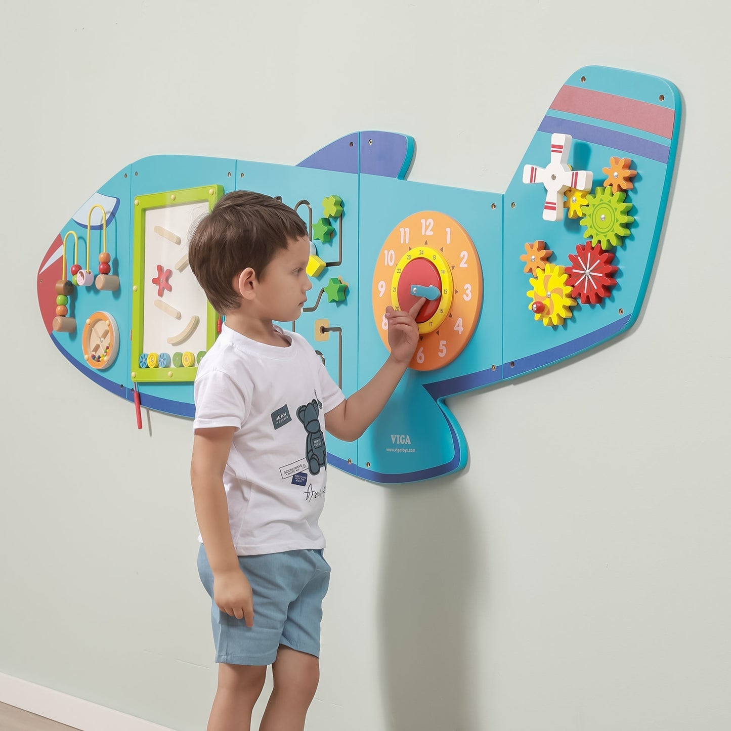 Child interacting with a colorful educational wall panel designed like an airplane.