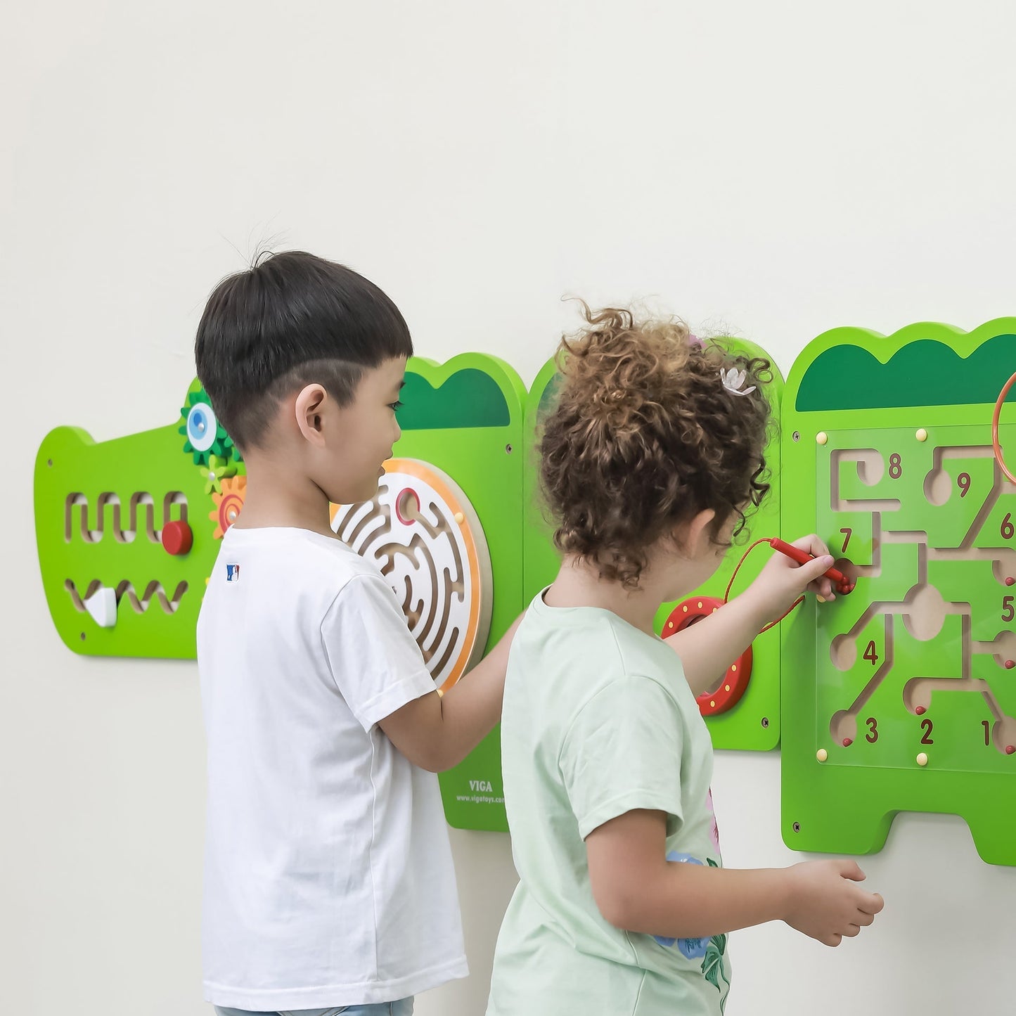 Two children playing with a maze wall game on a white background
