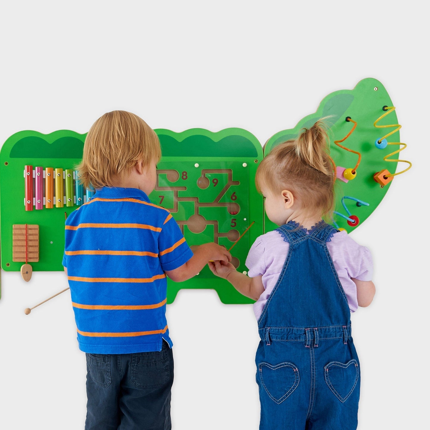Two children interacting with a colorful educational wall panel.