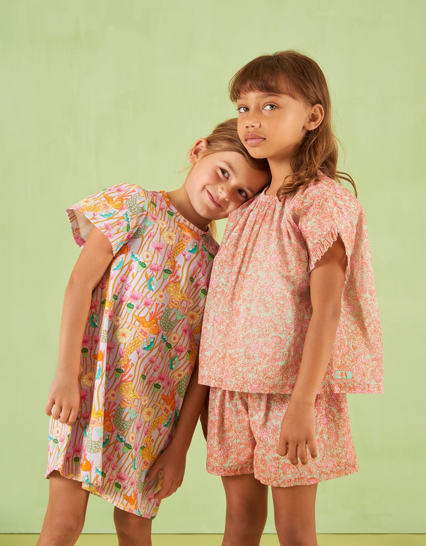 Two young girls wearing colorful Oilily outfits against a light green background