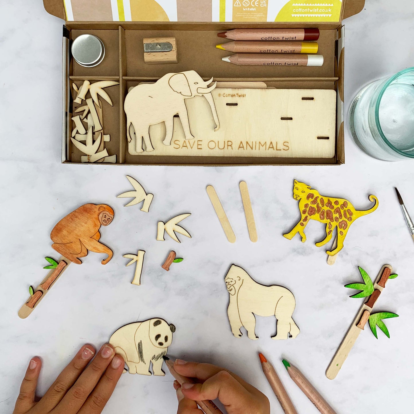 Wooden animal cutouts with 'Save Our Animals' message on a table with coloring supplies.