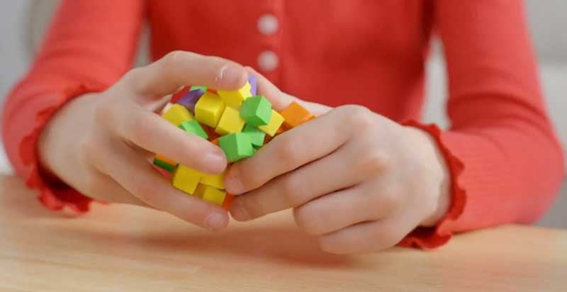 Child holding a handful of Fidlbitz colourful sticky building squares