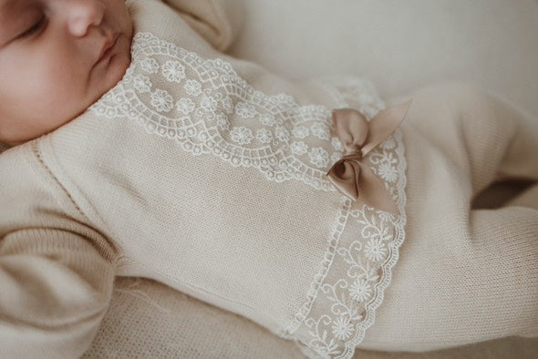 Baby wearing a beige outfit with lace details