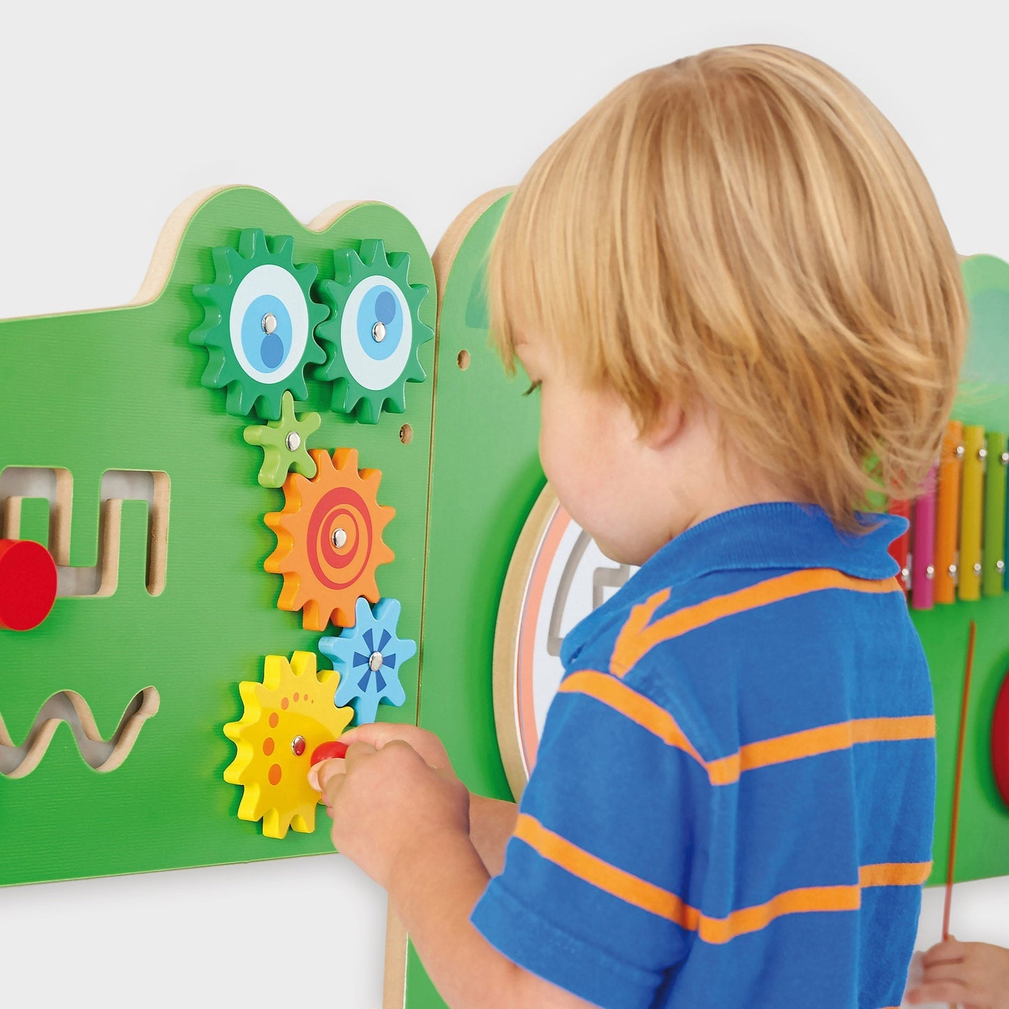 Child playing with a colorful educational board featuring gears and shapes.