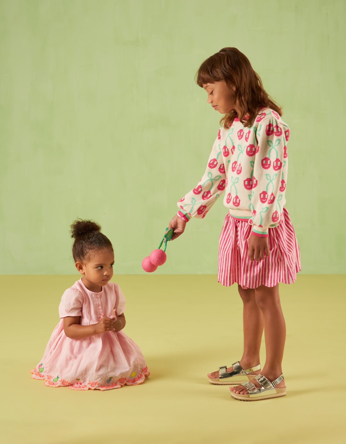 Two children in Oilily outfits against a green background