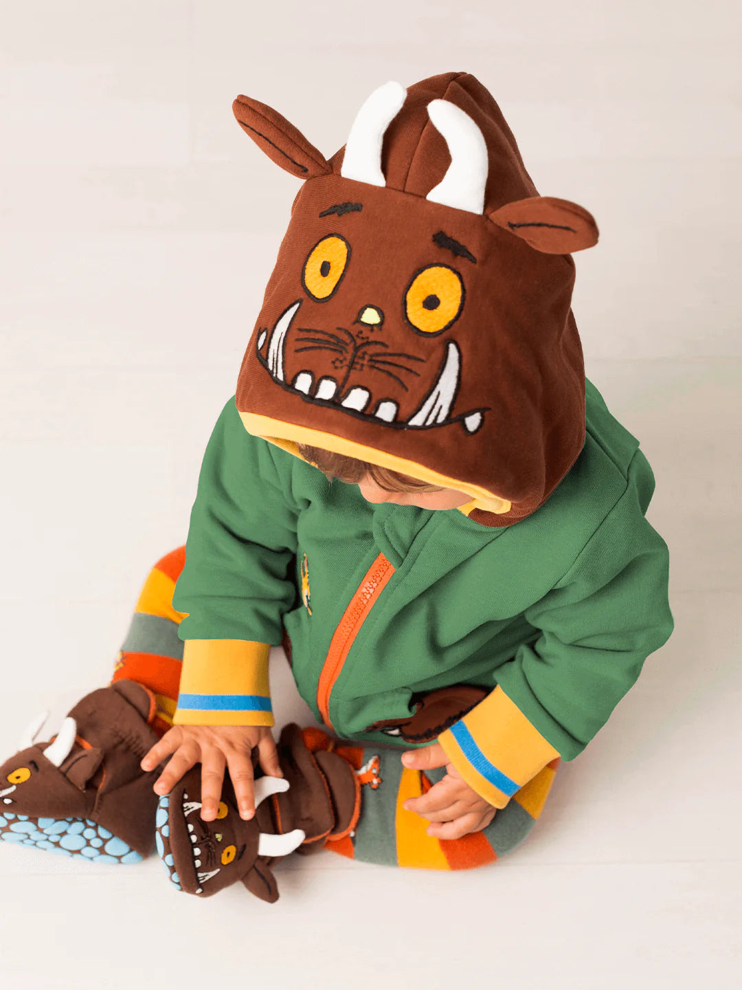 Child wearing a Gruffalo hoodie with a green outfit on a white background