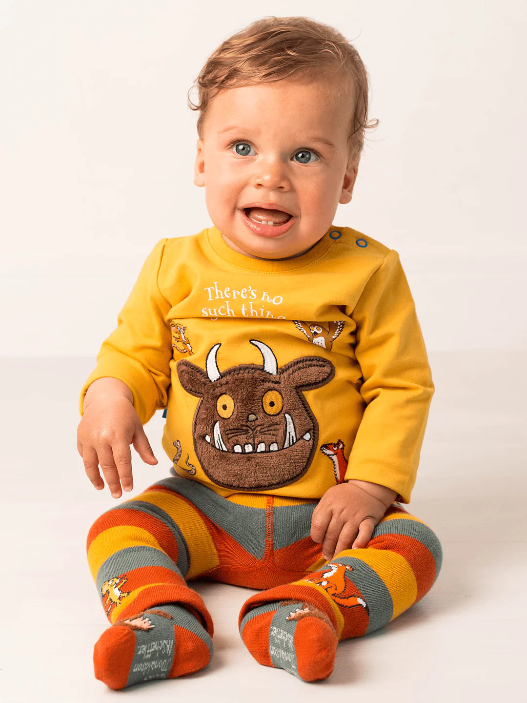 Baby wearing a yellow outfit with a gruffalo character on a white background