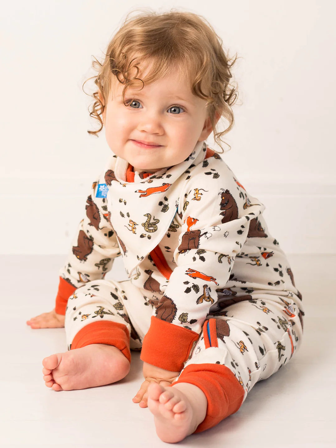 Child wearing a gruffalo patterned outfit with orange accents on a white background