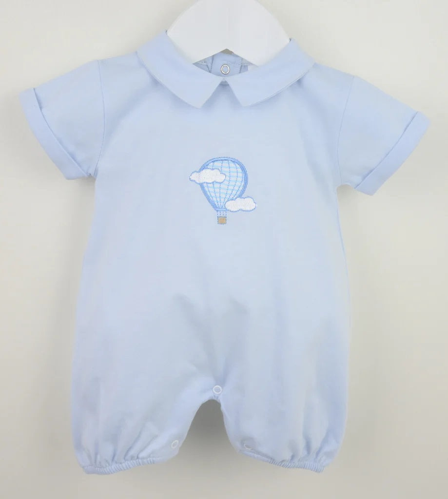 Light blue baby romper with hot air balloon design on a cream background
