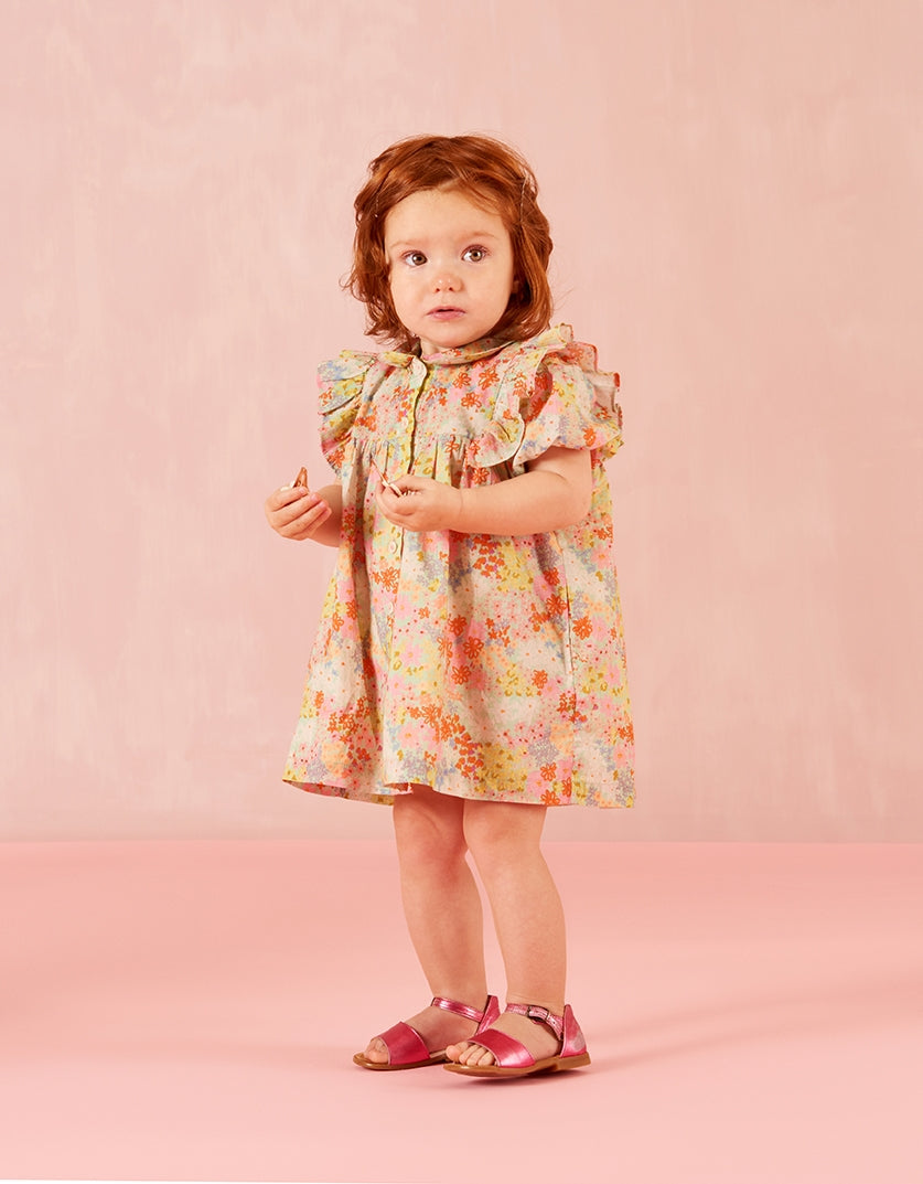 Young girl wearing a floral dress against a pink background