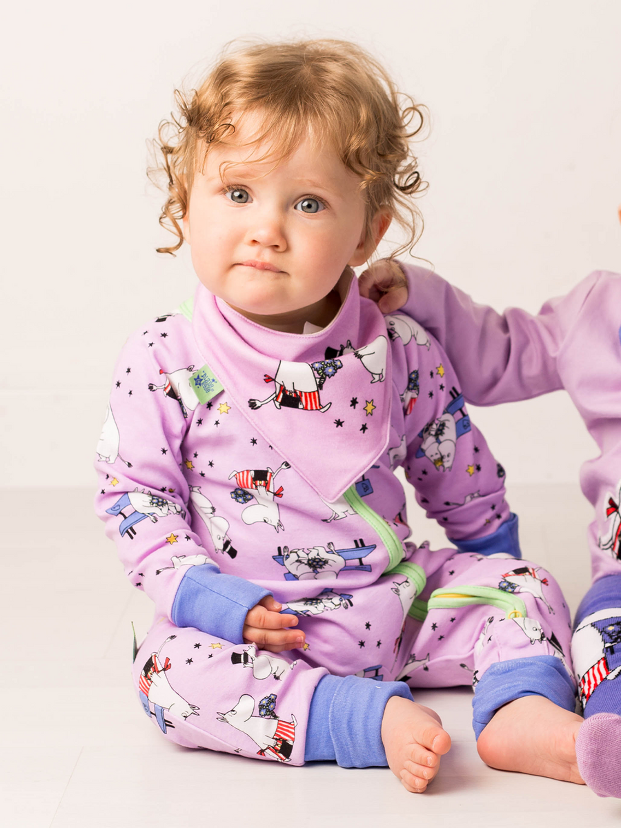 Child wearing a purple pajama set with cartoon characters on a light background