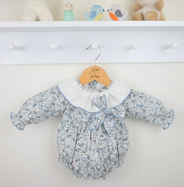 Floral baby romper on a hanger with a white background