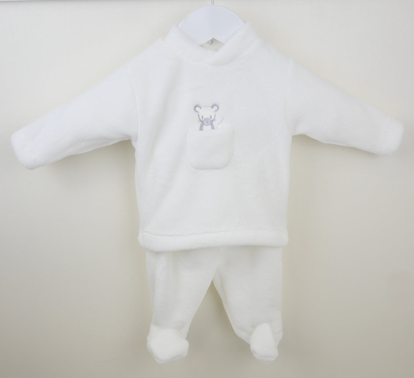 White baby outfit with a small mouse on a beige background