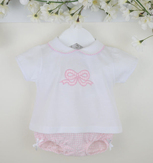 Baby outfit with white shirt and pink bow, paired with pink checkered bloomers on a light background.