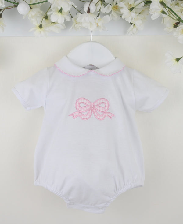 White baby romper with pink bow design on a light background