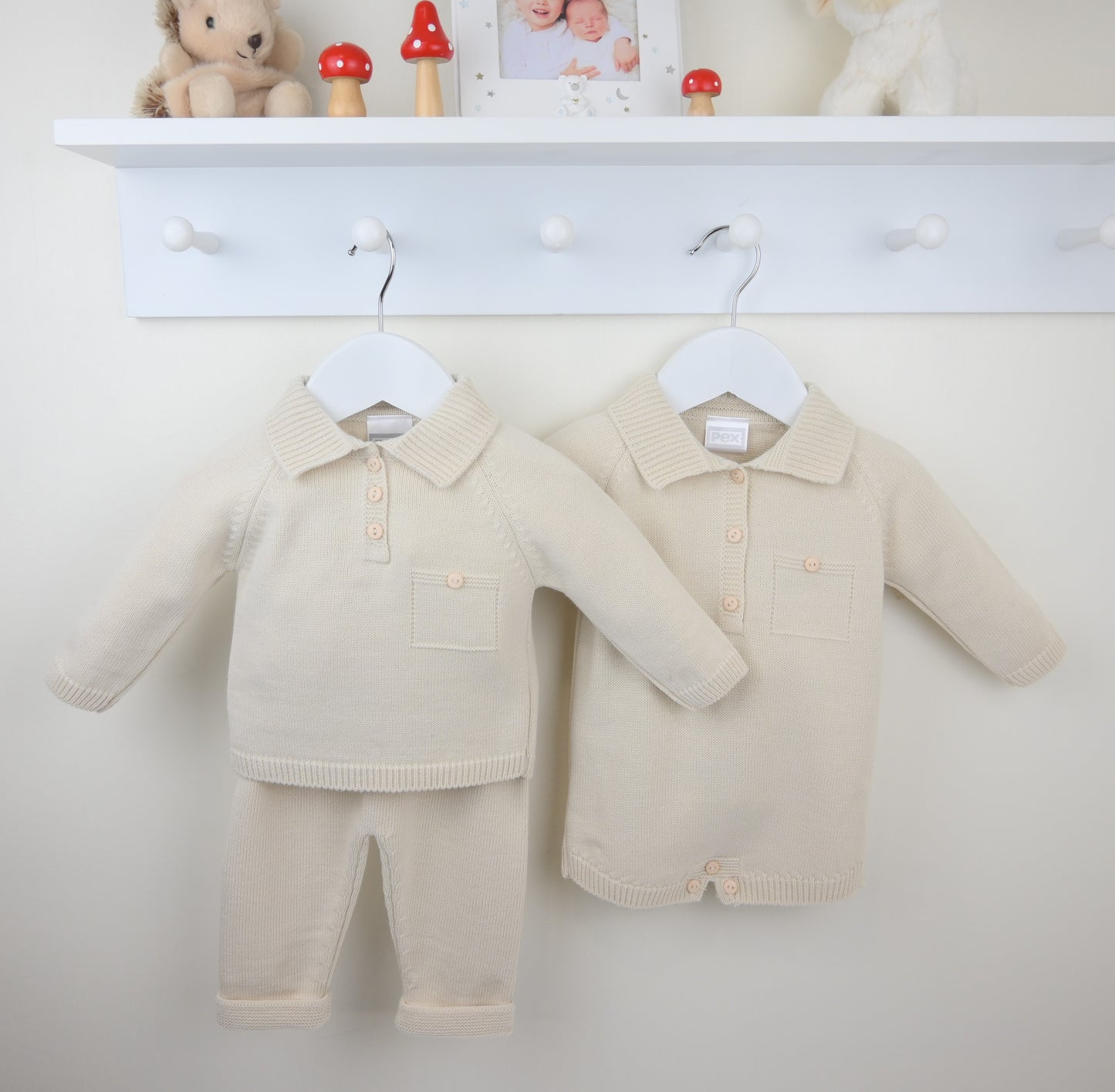 Pex beige baby outfits hanging on a white wall.