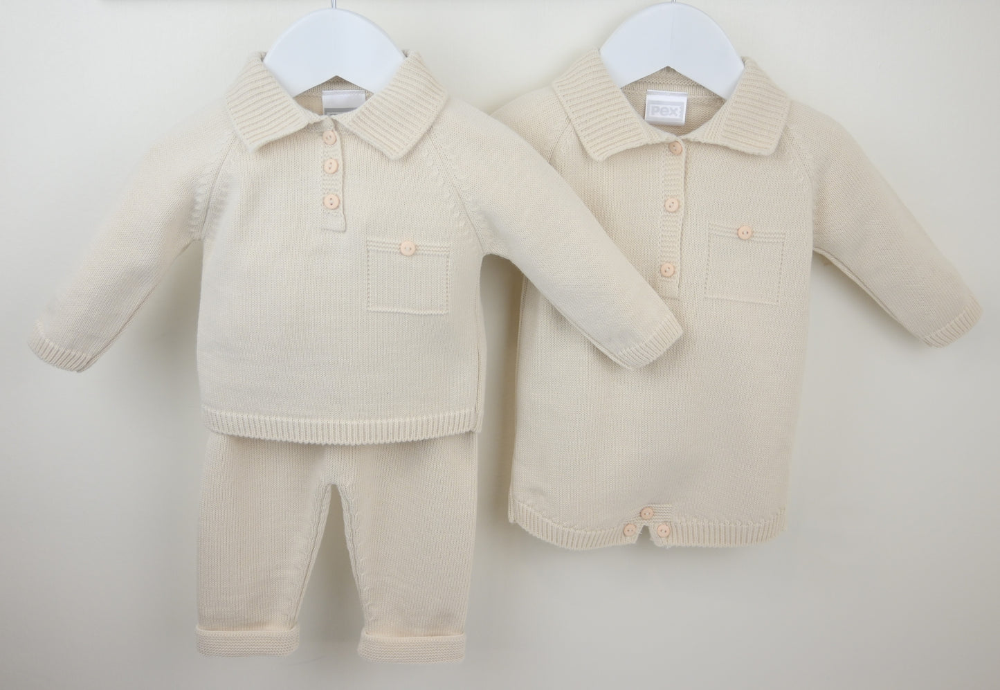 Beige baby outfits with shirt, pants, and rompers on hangers against a white background