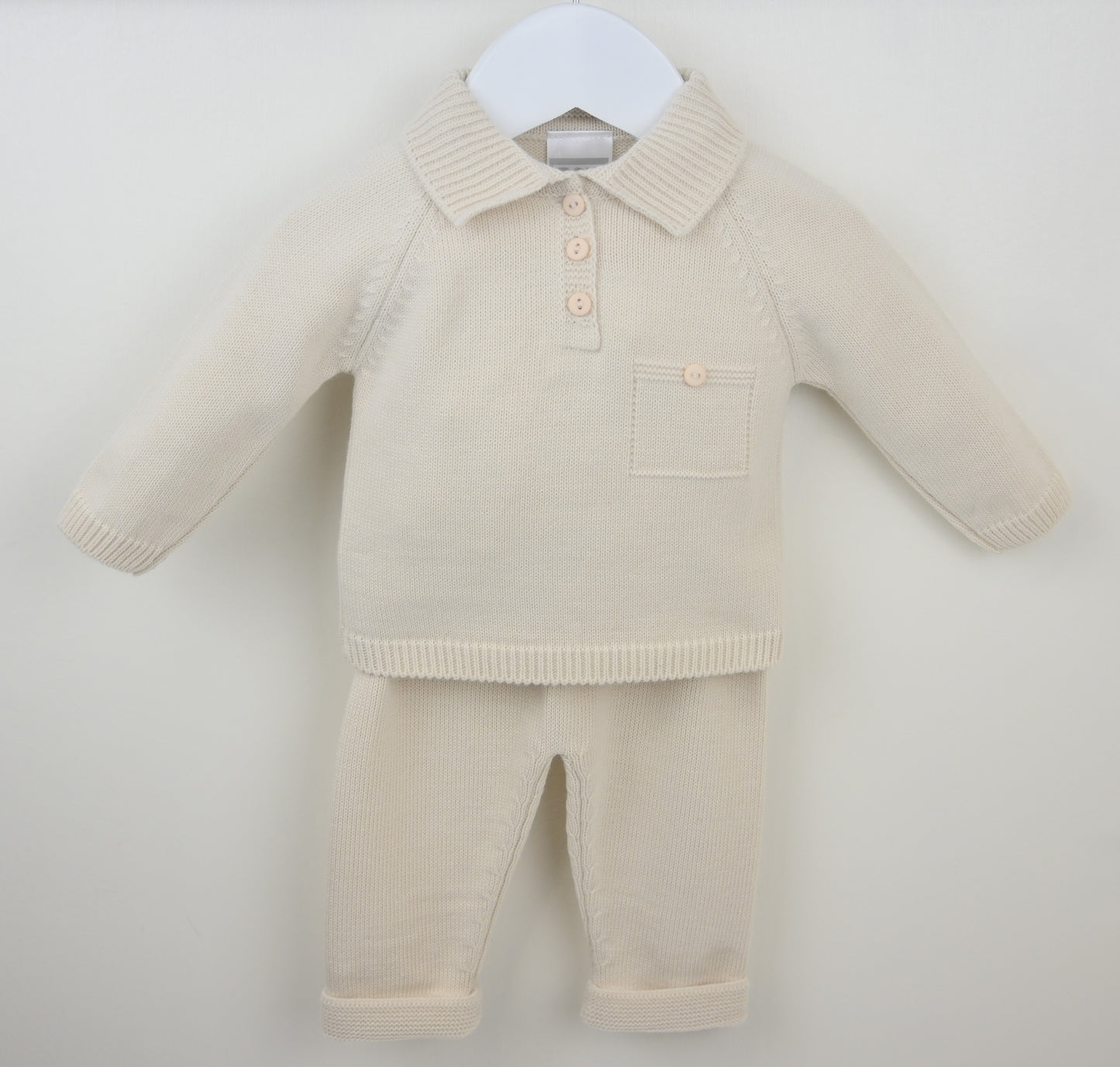 Beige knitted baby outfit with a shirt and pants on a white background