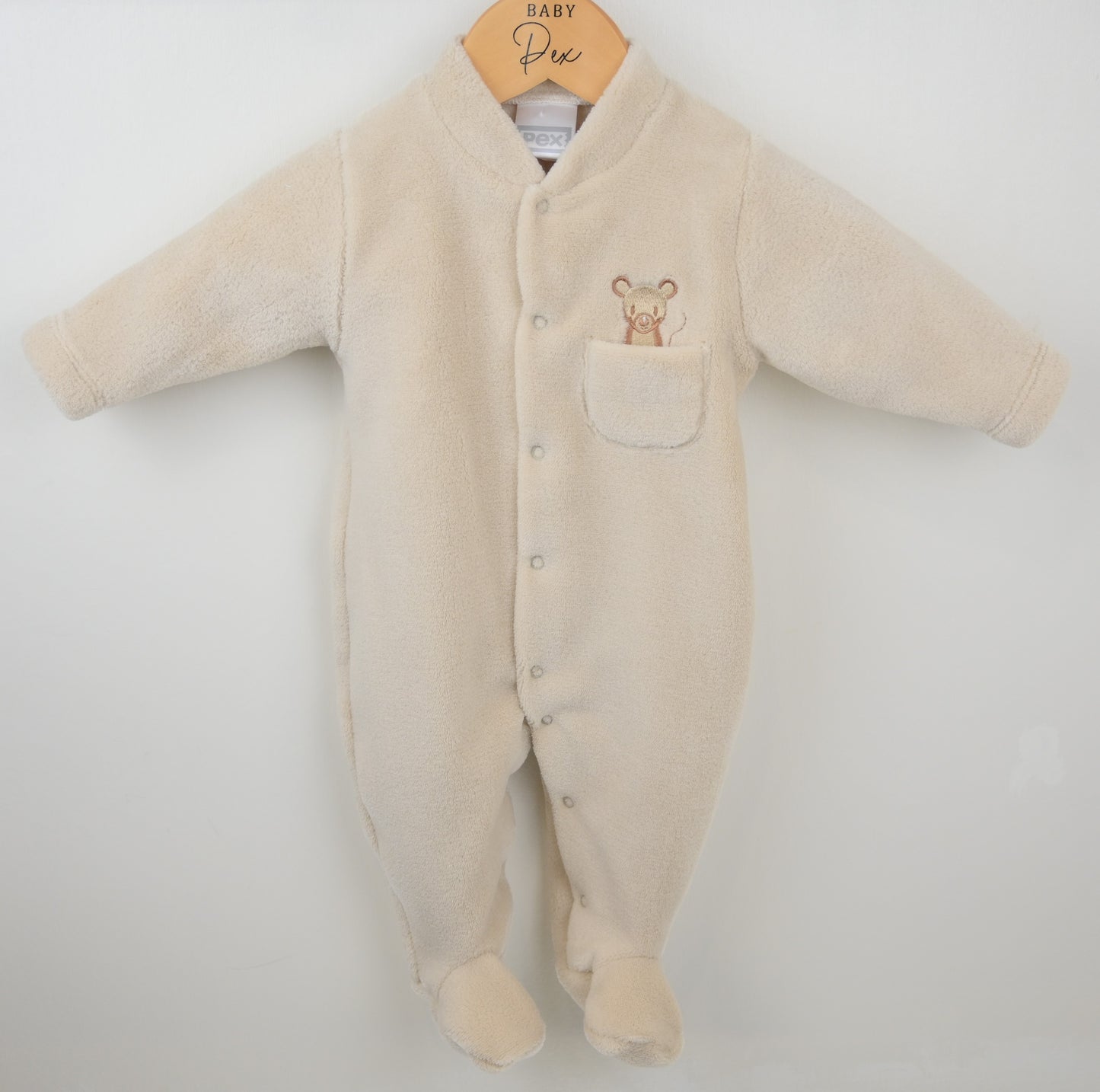 Beige baby onesie with a pocket and embroidered design on a white background