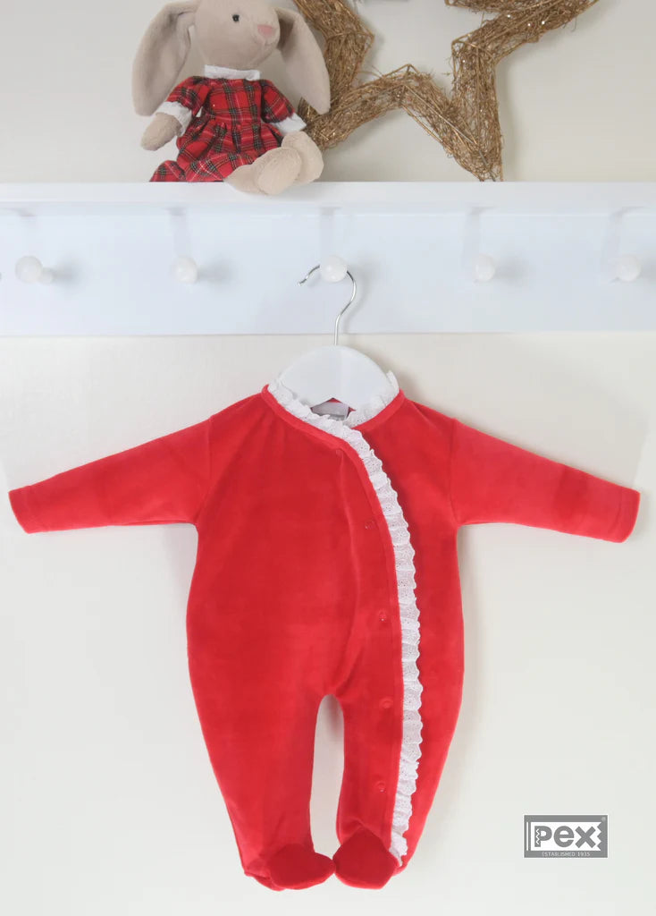 Red baby sleepsuit with white lace edging hanging on a white shelf.