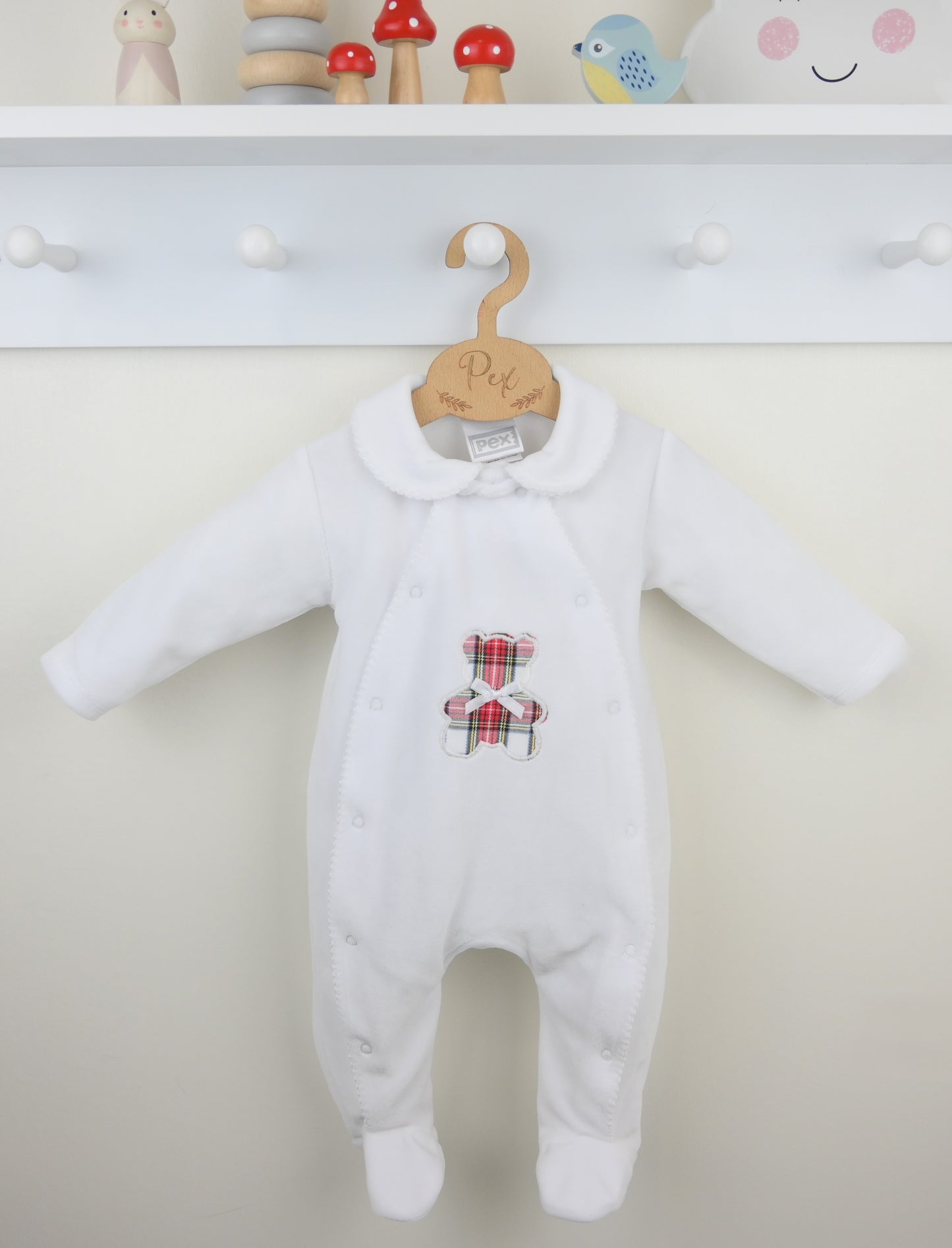 White baby onesie with a teddy bear design on a hanger against a white background