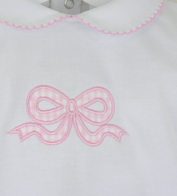 White fabric with a pink embroidered bow design on a white background
