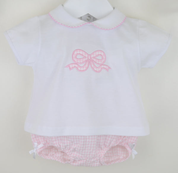 Baby outfit with white shirt and pink shorts on a beige background