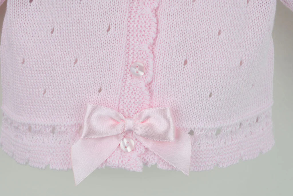 Pink knitted garment with a bow detail on a light gray background