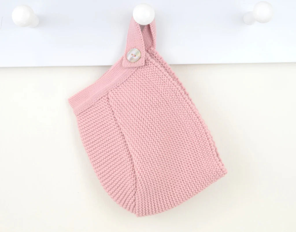 Pink knitted bonnet with buttons on a white background