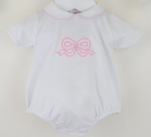 White baby romper with pink bow design on a beige background
