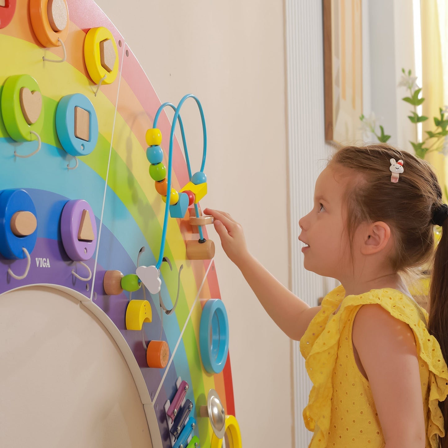 Child playing with a colorful educational toy in a bright room.