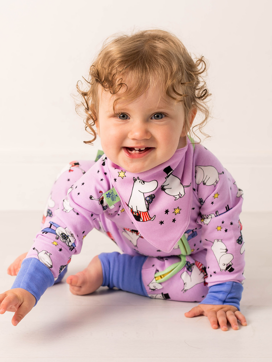 Child wearing a purple pajama set with cartoon characters on a white background