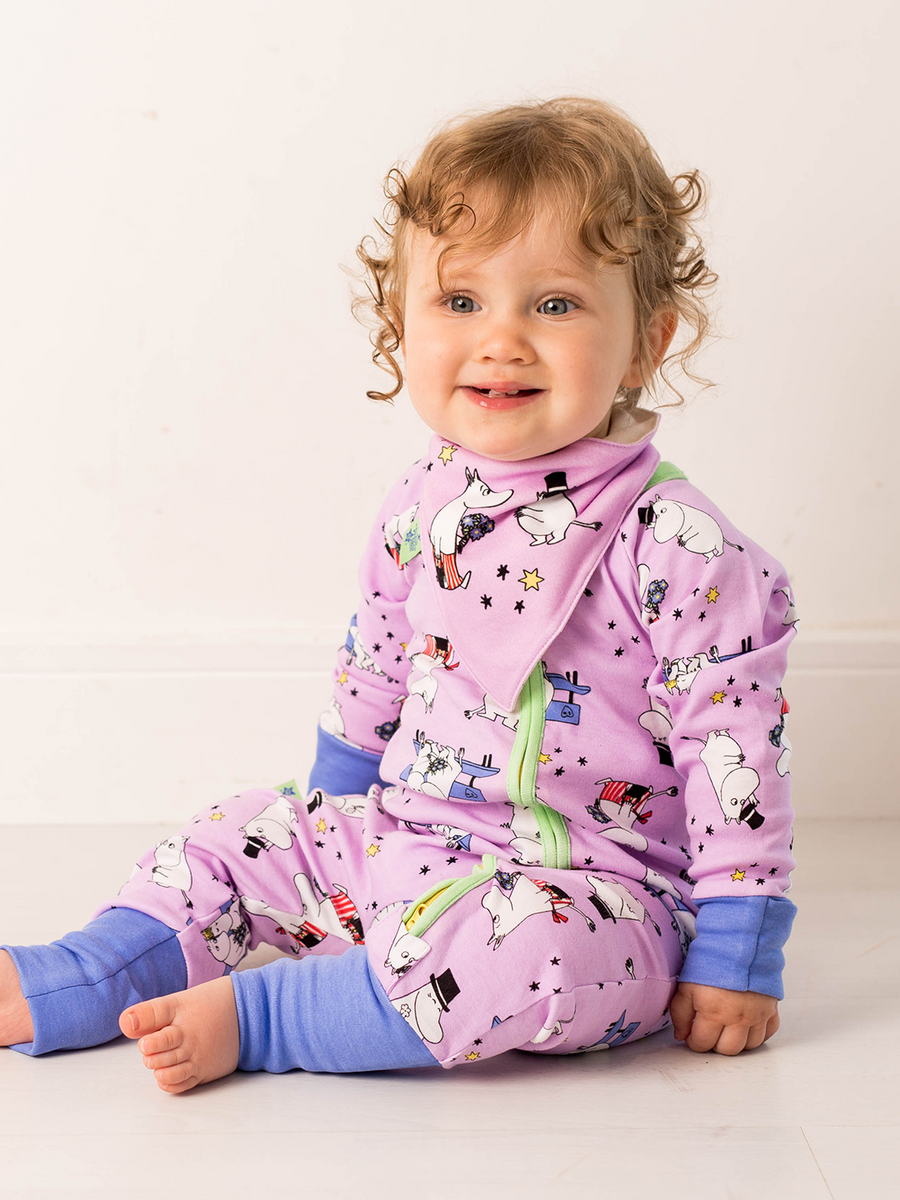 Baby wearing a purple onesie with cartoon characters on a white background