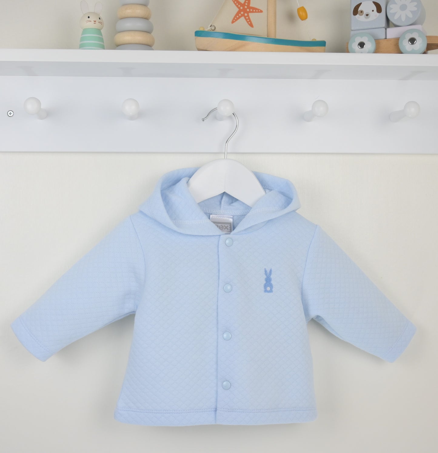 Light blue baby jacket on a hanger against a white background with toys in the background.