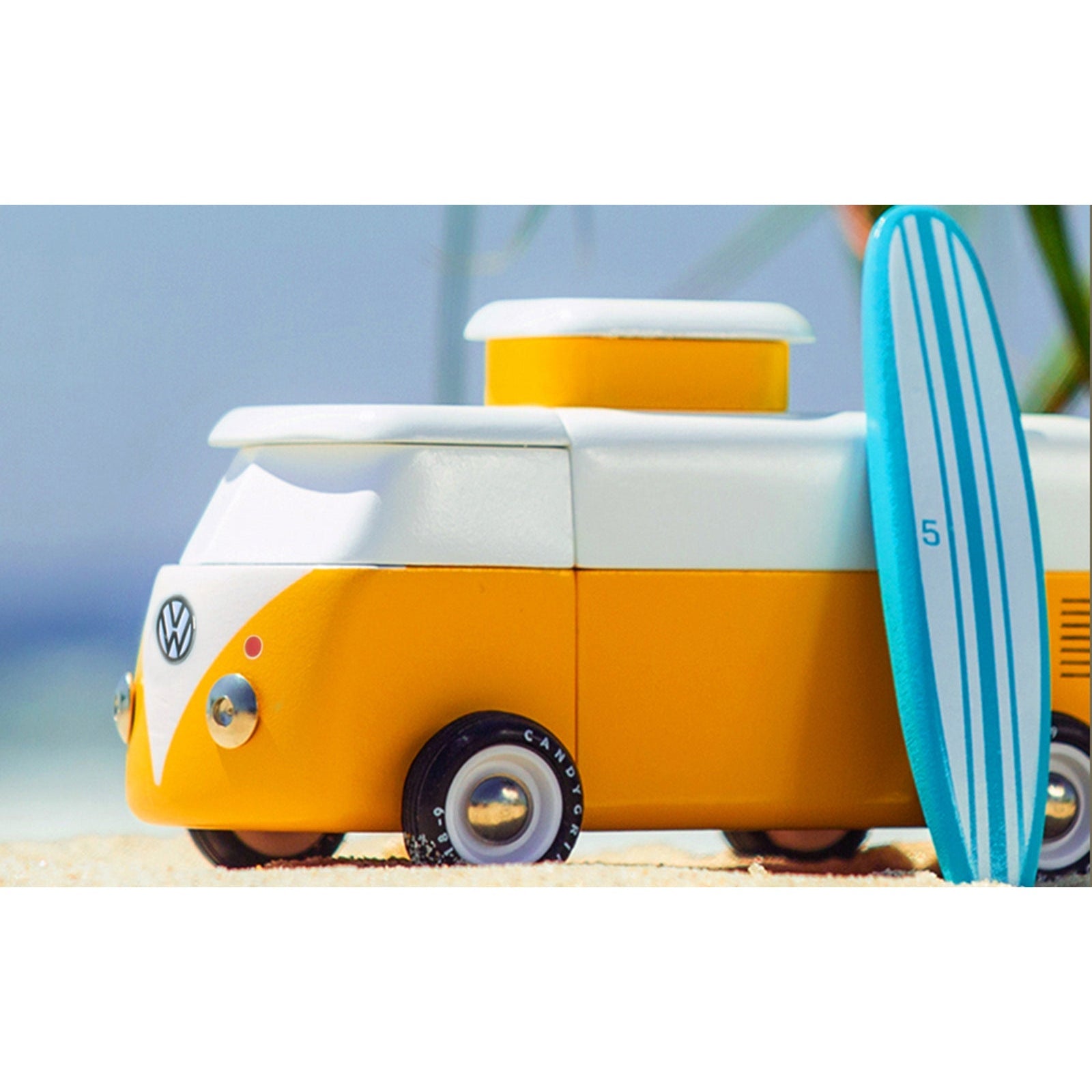 Toy Volkswagen van with a surfboard on a beach