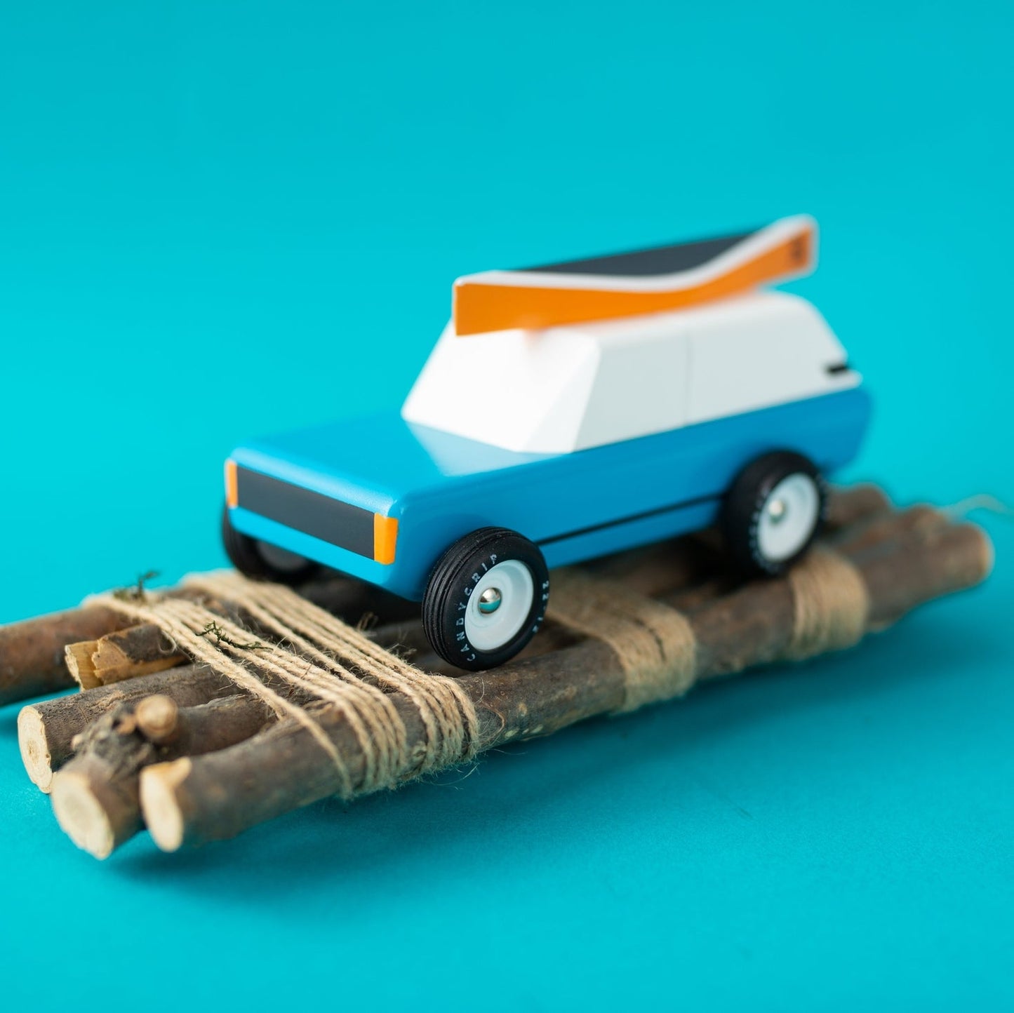 Toy car on a makeshift road made of sticks against a blue background