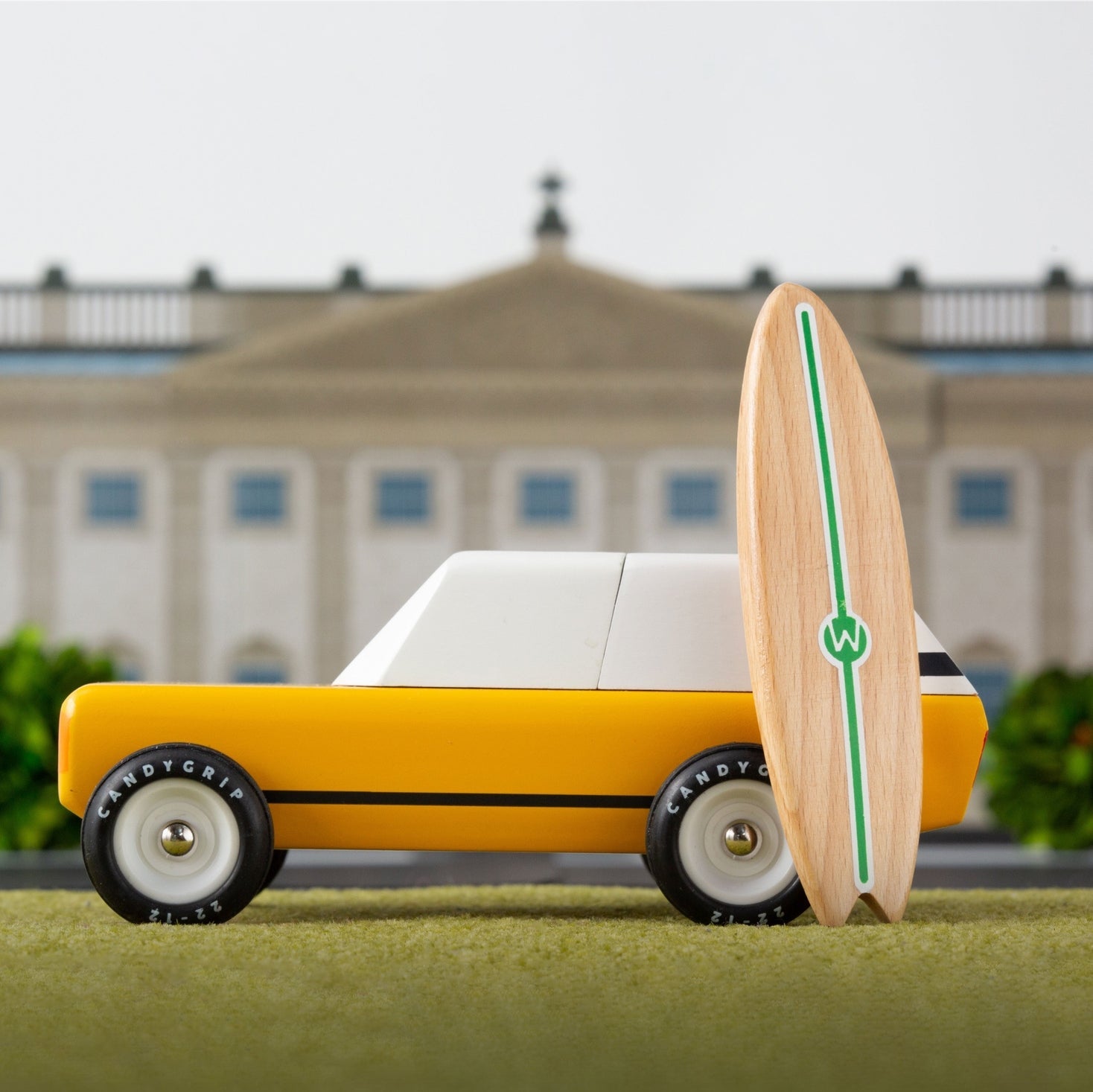 Toy car with a wooden wheel in front of a building