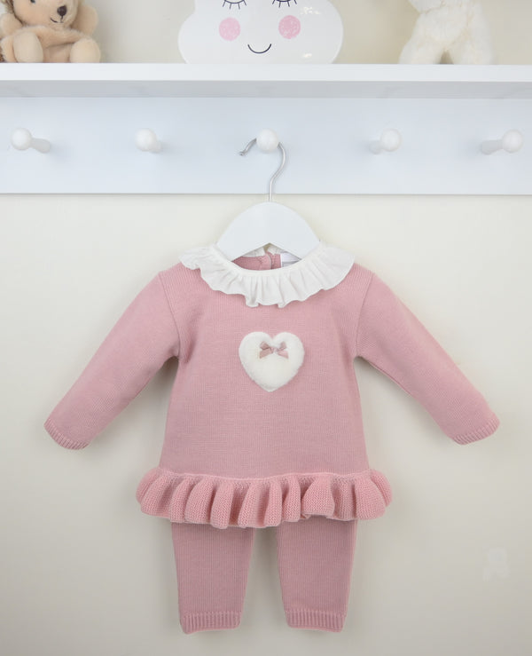 Pink baby outfit with white heart and bow on a hanger against a white background
