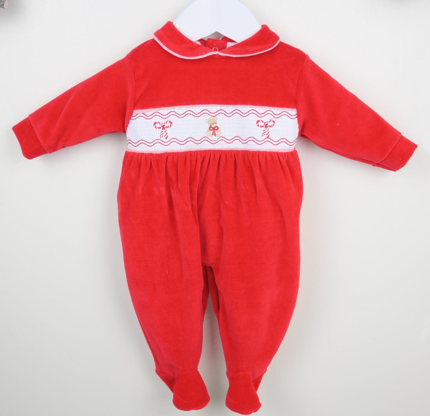 Red baby onesie with white Christmas embroidery on a white background