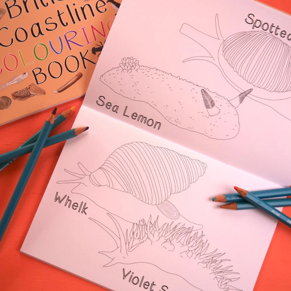 Coloring book with sea-themed illustrations and coloring pencils on an orange surface